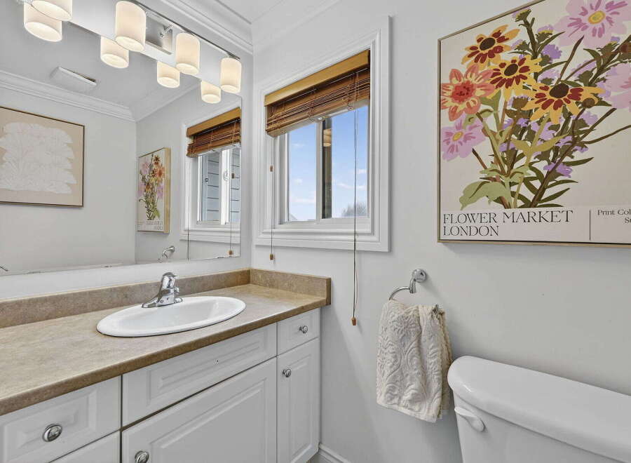 This charming bathroom features a bright and airy design with a large mirror and a stylish vanity.