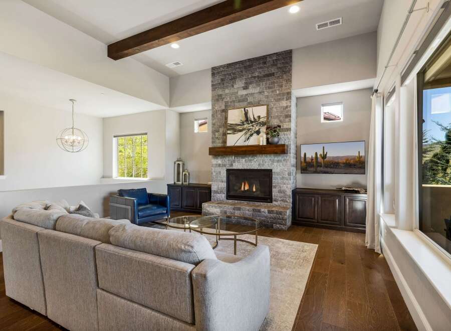 Step into luxury with this stunning living room, featuring a striking stone fireplace and a cozy seating area.