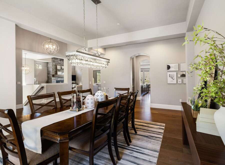 This elegant dining room features a stunning chandelier and a beautiful dark wood dining table.