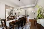 This elegant dining room features a stunning chandelier and a beautiful dark wood dining table.