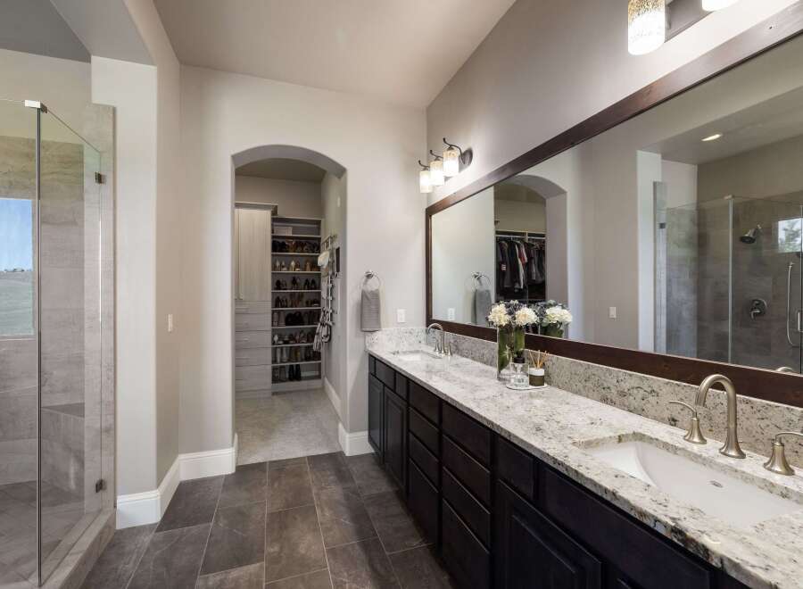 Step into luxury with this stunning bathroom, featuring a spacious walk-in shower and a double vanity with elegant granite countertops.