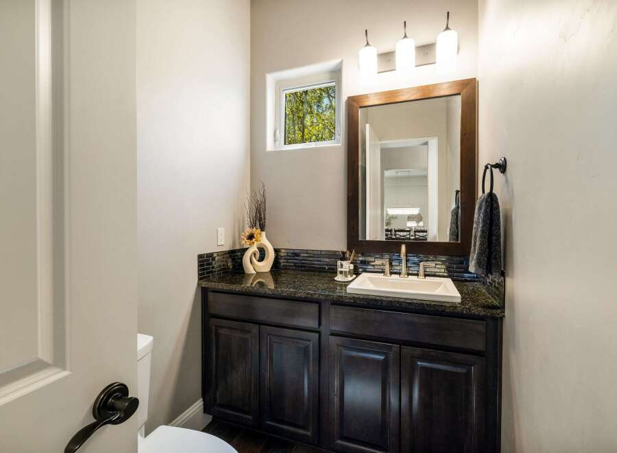 This stunning bathroom features a modern vanity with a dark granite countertop and sleek cabinetry.