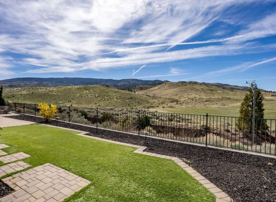 Enjoy breathtaking views from this stunning property! This home features a beautifully landscaped backyard with lush green grass and a charming stone pathway.