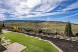 Enjoy breathtaking views from this stunning property! This home features a beautifully landscaped backyard with lush green grass and a charming stone pathway.