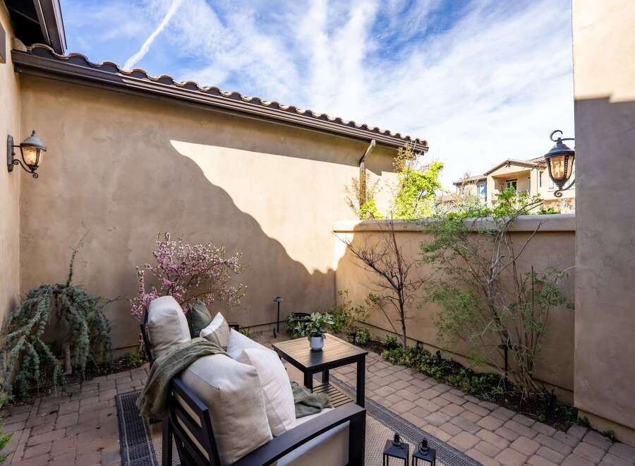 Enjoy the tranquility of this private outdoor oasis! This stunning patio features comfortable seating, a charming table, and lush greenery, perfect for relaxing or entertaining.