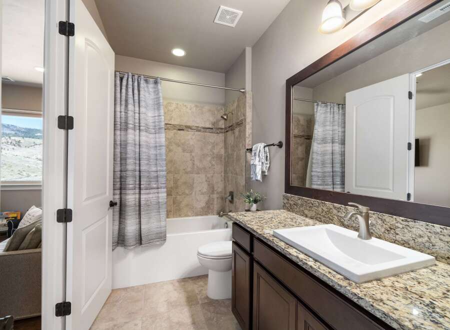 Step into this beautifully designed bathroom, featuring a modern vanity with a granite countertop and a sleek, undermount sink.