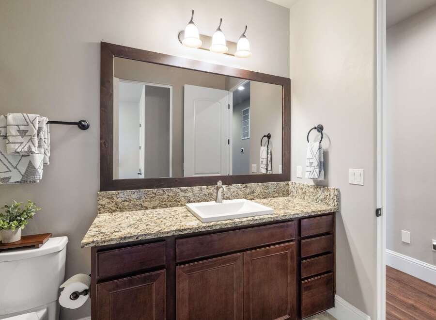 This stunning bathroom features a modern vanity with a granite countertop and dark wood cabinetry, offering ample storage space.