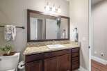 This stunning bathroom features a modern vanity with a granite countertop and dark wood cabinetry, offering ample storage space.