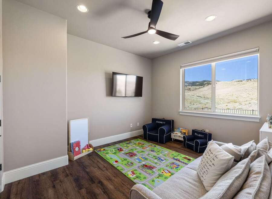 This inviting playroom is perfect for kids, featuring a vibrant play mat, comfortable seating, and a mounted TV for entertainment.