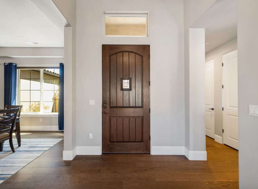Step into this inviting entryway, showcasing a stunning wooden front door and elegant hardwood floors.