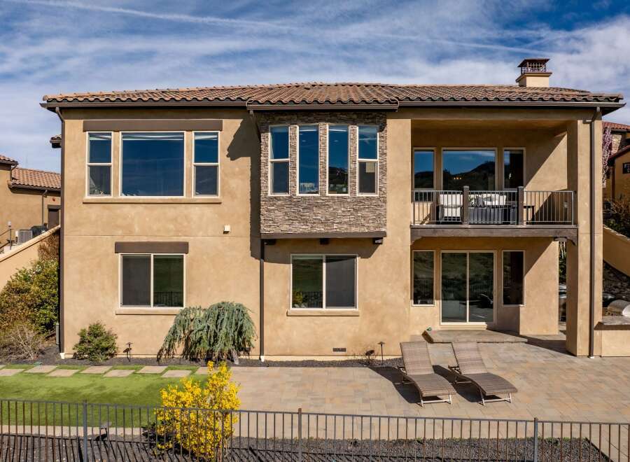 Discover luxury living in this stunning two-story home, featuring a beautiful stone facade and a tiled roof.