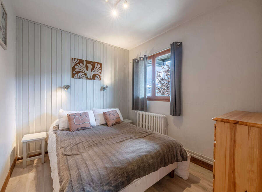 This cozy bedroom offers a serene retreat with its warm wooden accents and inviting ambiance.