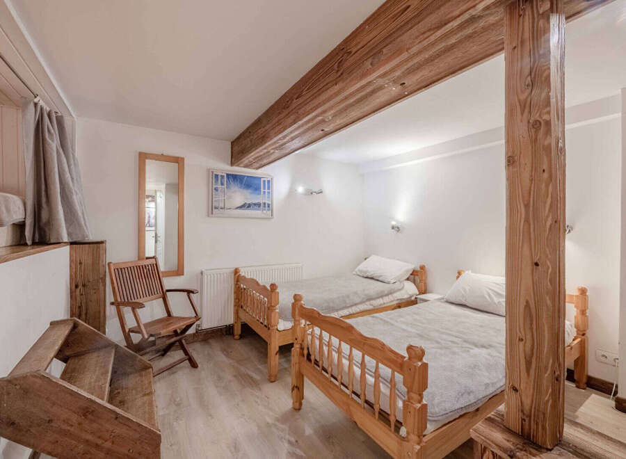 This cozy bedroom features two twin beds with wooden frames, perfect for a comfortable stay.