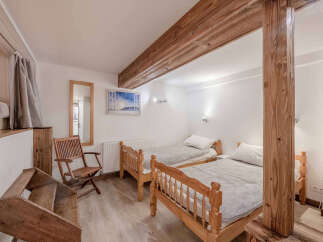 This cozy bedroom features two twin beds with wooden frames, perfect for a comfortable stay.