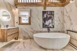 This luxurious bathroom features a stunning marble tile design, a modern soaking tub, and a stylish vanity.