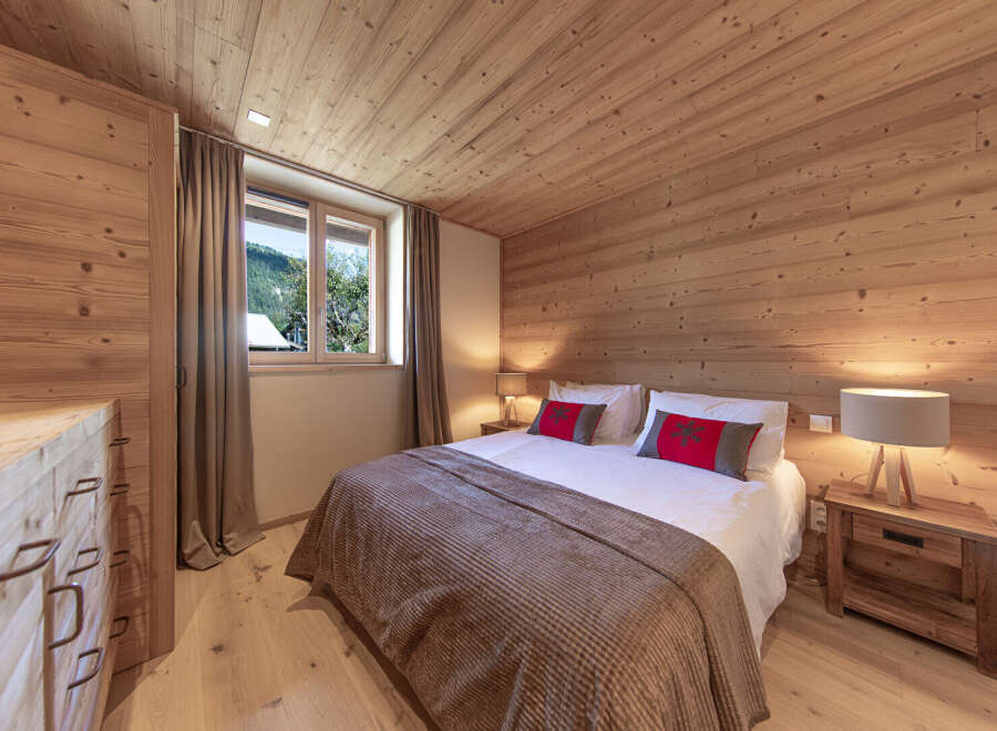 Experience the warmth of this inviting bedroom, featuring stunning wood paneling on the walls and ceiling.