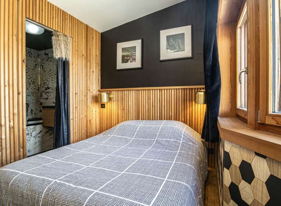 This cozy bedroom features a unique design with wooden paneling and a stylish geometric accent wall.
