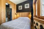 This cozy bedroom features a unique design with wooden paneling and a stylish geometric accent wall.