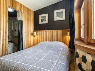 This cozy bedroom features a unique design with wooden paneling and a stylish geometric accent wall.
