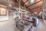 Experience luxury living in this stunning chalet-style home, featuring a spacious open-plan living area with exposed wooden beams and a cozy fireplace.