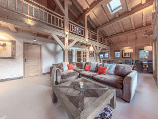 Experience luxury living in this stunning chalet-style home, featuring a spacious open-plan living area with exposed wooden beams and a cozy fireplace.