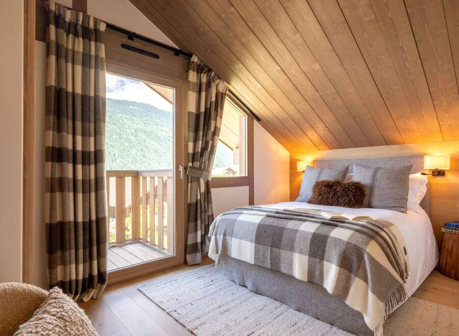 Experience the charm of this cozy bedroom, featuring a stunning mountain view from the balcony.