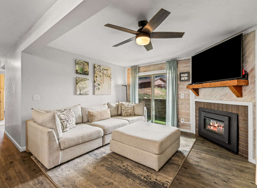 This cozy living room features a comfortable sectional sofa and a stylish ottoman, perfect for relaxing.