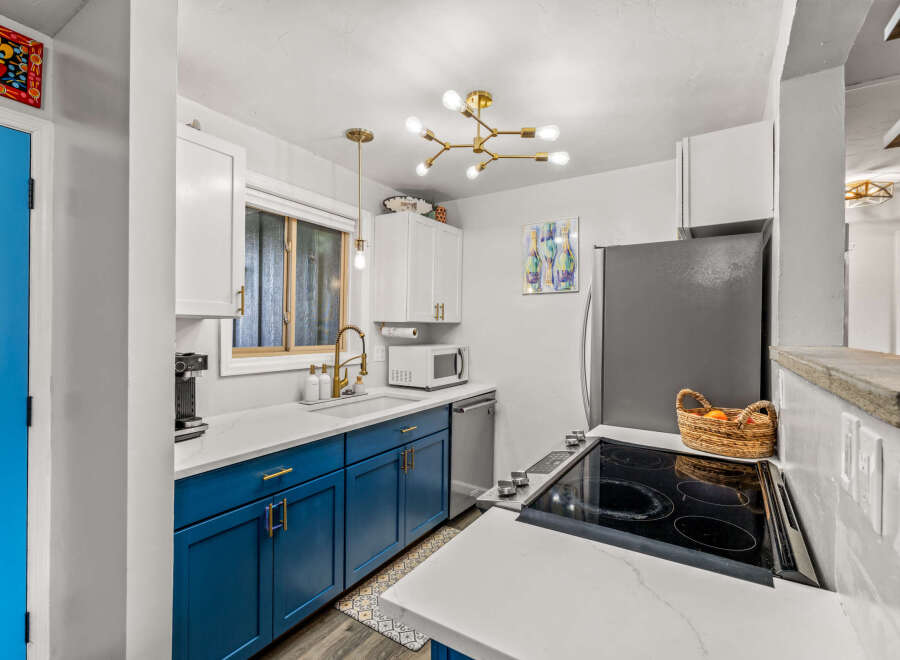 This stunning kitchen boasts a modern design with sleek blue cabinetry and pristine white countertops, creating a bright and inviting space.
