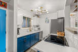 This stunning kitchen boasts a modern design with sleek blue cabinetry and pristine white countertops, creating a bright and inviting space.