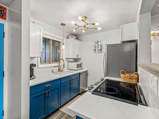 This stunning kitchen boasts a modern design with sleek blue cabinetry and pristine white countertops, creating a bright and inviting space.