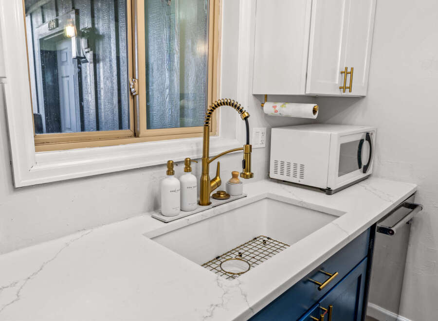 This stunning kitchen boasts a modern design with sleek white countertops and vibrant blue cabinetry, creating a stylish and inviting atmosphere.