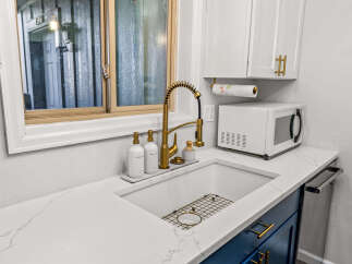 This stunning kitchen boasts a modern design with sleek white countertops and vibrant blue cabinetry, creating a stylish and inviting atmosphere.