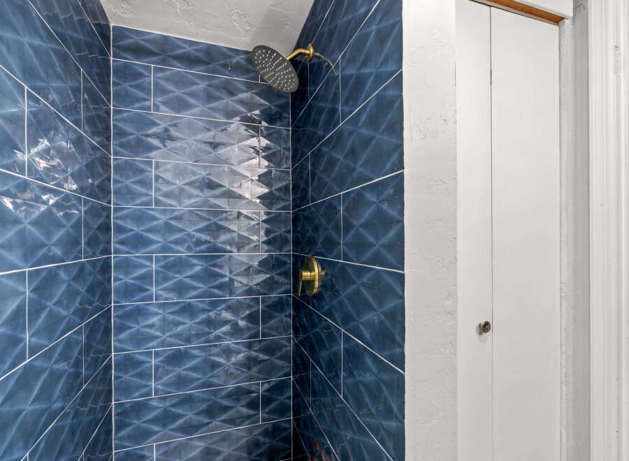 Step into luxury with this stunning bathroom! Featuring exquisite blue tile work and a modern shower head, this space is designed for ultimate relaxation.