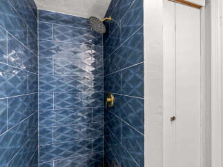 Step into luxury with this stunning bathroom! Featuring exquisite blue tile work and a modern shower head, this space is designed for ultimate relaxation.