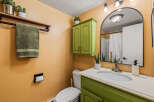 This charming bathroom features a unique green vanity and cabinet, adding a pop of color to the space.