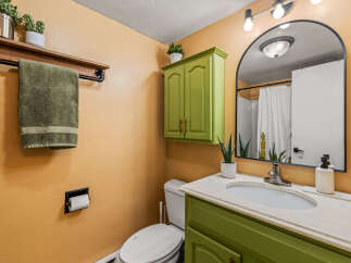 This charming bathroom features a unique green vanity and cabinet, adding a pop of color to the space.
