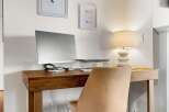 Discover the perfect workspace in this stylish home office! Featuring a sleek wooden desk, a comfortable chair, and a modern computer setup, this space is designed for productivity and comfort.