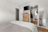 This inviting bedroom features a stylish wooden dresser, perfect for storage and adding a touch of warmth.