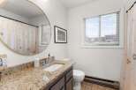 This bathroom features a stylish round mirror, a granite countertop, and a modern sink.