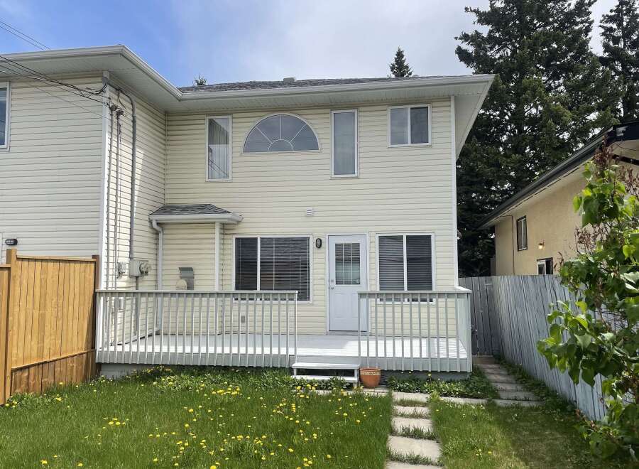 This charming two-story home boasts a welcoming exterior with a spacious deck, perfect for outdoor relaxation and entertaining.