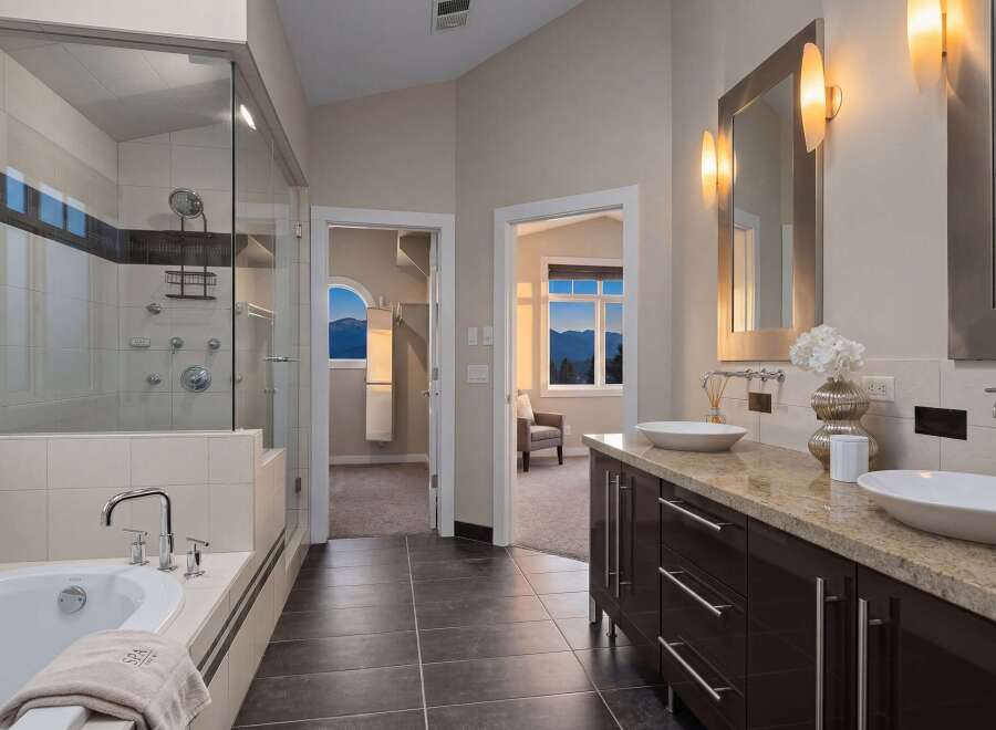 Step into luxury with this stunning bathroom featuring a sleek glass shower, a relaxing bathtub, and elegant double sinks.