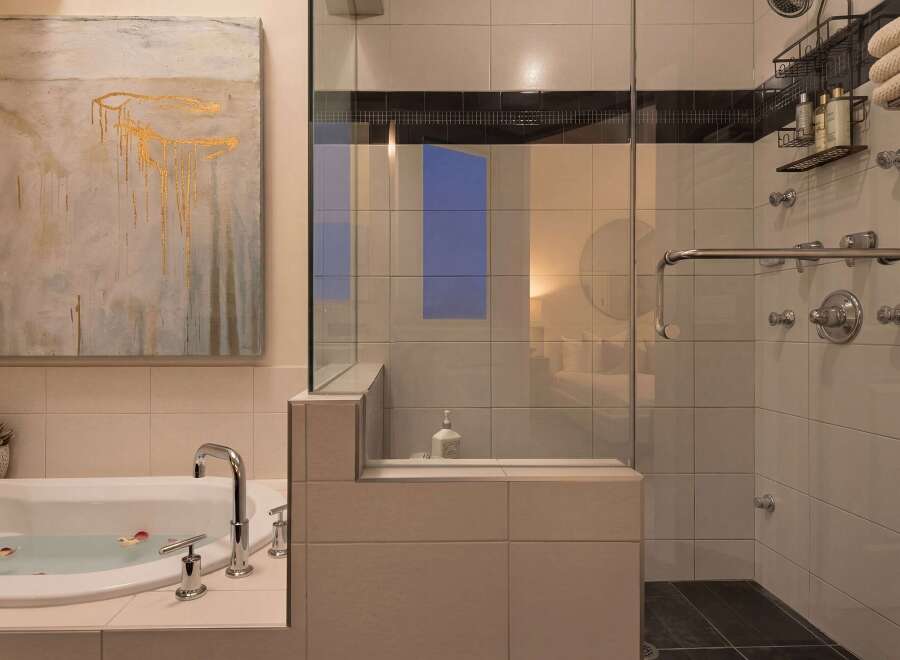 Indulge in luxury within this stunning bathroom, featuring a sleek glass-enclosed shower and a relaxing soaking tub.