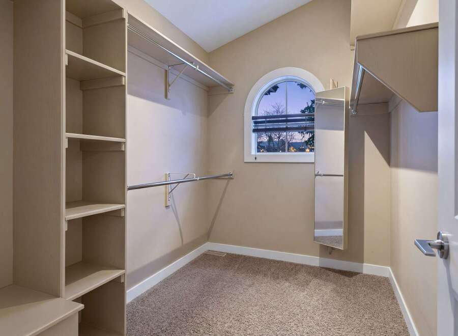 Step into this spacious walk-in closet, offering ample storage with its built-in shelving and hanging rods.