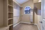 Step into this spacious walk-in closet, offering ample storage with its built-in shelving and hanging rods.