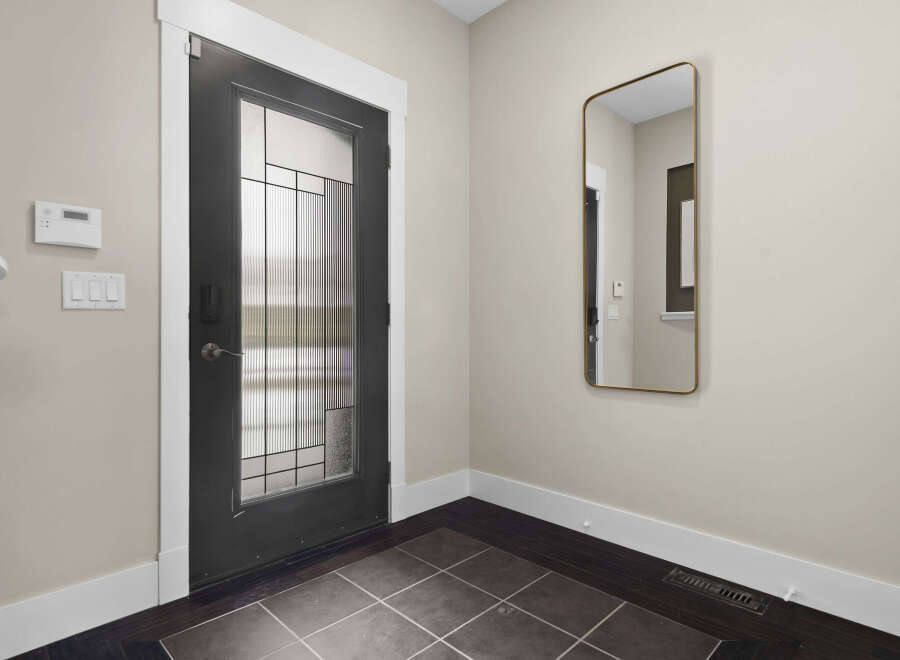 Step into this inviting entryway, showcasing a modern front door with a glass panel design.