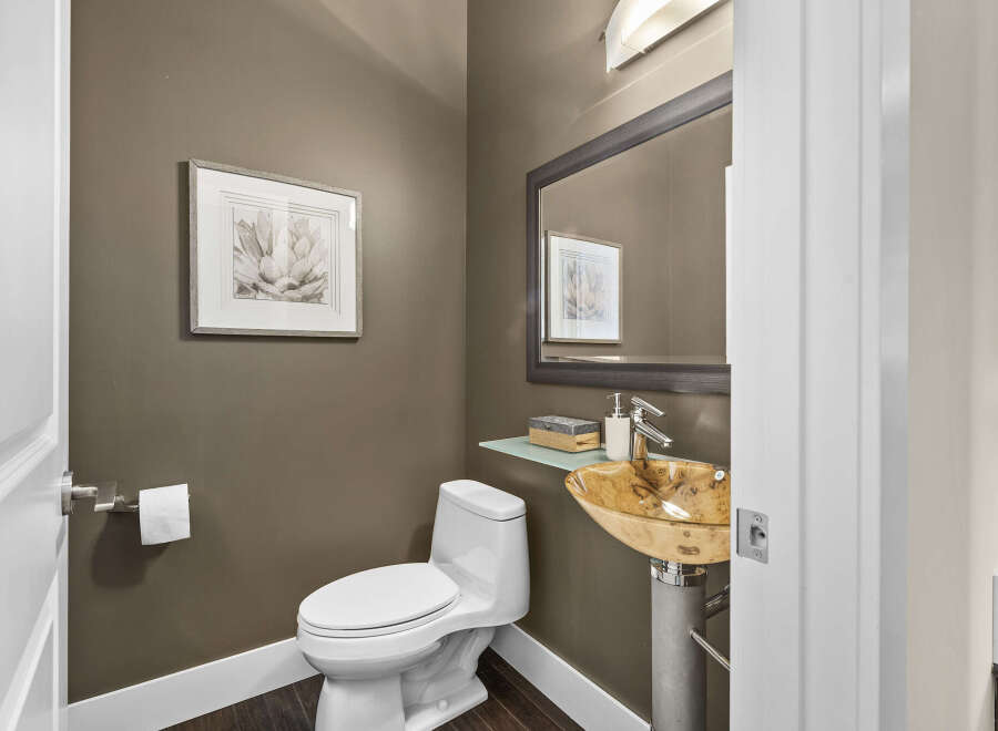 This stunning powder room showcases a modern design with a unique vessel sink and elegant fixtures.