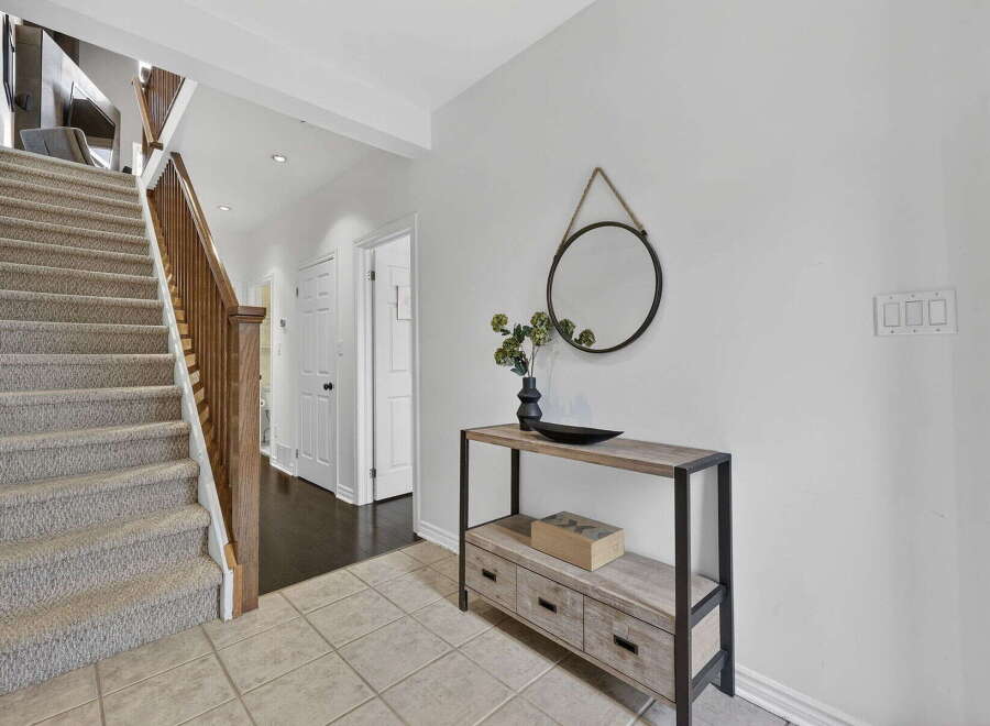 Step into this inviting entryway, showcasing a stunning staircase with carpeted steps and a warm wooden banister.