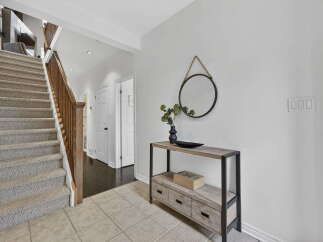 Step into this inviting entryway, showcasing a stunning staircase with carpeted steps and a warm wooden banister.