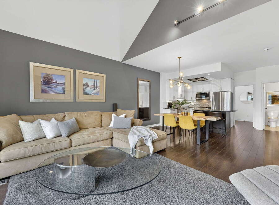 Step into luxury with this stunning property, featuring a spacious living area with a cozy sectional sofa and a modern glass coffee table.