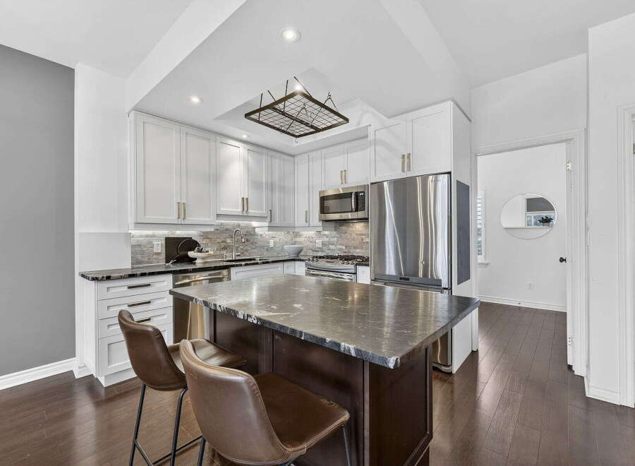 This stunning kitchen boasts a modern design with sleek white cabinetry and a contrasting dark island.